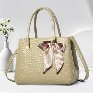 Detail of light green tote bag with woven texture and a decorative striped silk ribbon bow