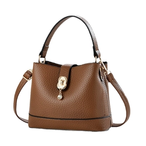 Brown litchi leather bucket bag with gold lock and bear charm from 45-degree angle