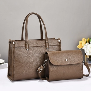 Close-up of brown litchi pattern leather tote bag and crossbody bag with silver hardware