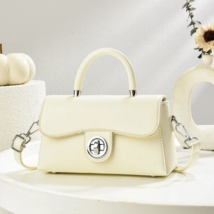 Minimalist beige crossbody bag with silver twist lock and elegant top handle shown in studio