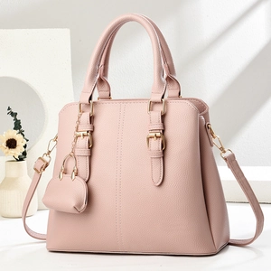 Detail of pink lychee textured handbag with golden hardware and matching mini charm pouch