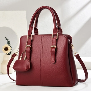 Close-up of burgundy leather handbag with litchi texture and golden metal hardware details