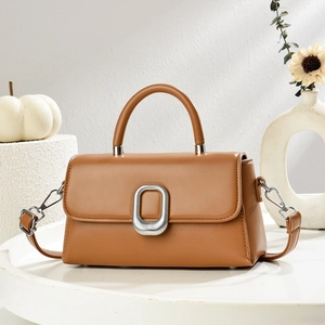 Caramel brown pebbled leather crossbody bag with silver oval buckle and top handle