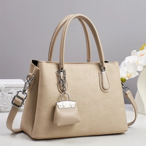 Détail du sac beige à texture tissée avec bandoulière amovible et mini pendentif