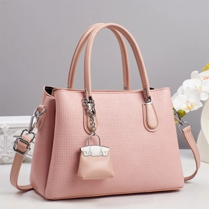 Détail d'un sac rose avec texture tressée, accents argentés et décor floral doux