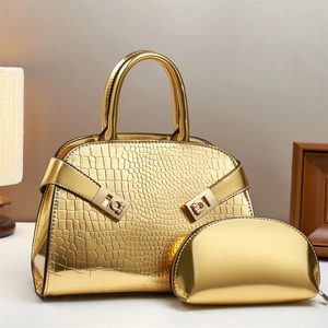 Close-up of gold croc-embossed handbag set with polished metallic hardware detail