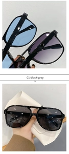 Detail of retro oval sunglasses with tinted lenses and textured white leather case