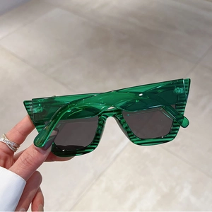 Close-up of translucent green cat-eye sunglasses with horizontal stripe texture