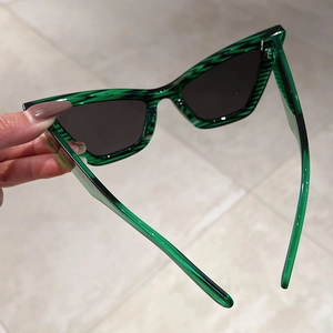 Detail of emerald green cat-eye sunglasses showing translucent striped resin frames