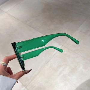 Close-up of translucent green cat-eye sunglasses frames in a stylish hand-held side view