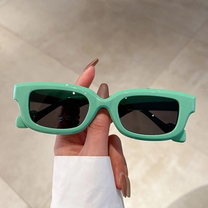 Chic mint green square frame sunglasses with dark grey lenses in a handheld display view