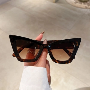 Detailed close-up of dark amber tortoiseshell cat-eye frames and gradient brown lenses
