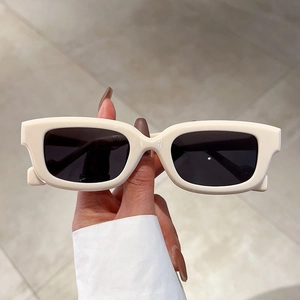 Detail showing thick cream rectangular frames and dark lenses of modern sunglasses
