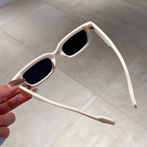 Detail view of retro cream square frame sunglasses with dark UV protection lenses