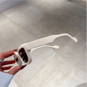 Close-up of cream square frame sunglasses with wide temples and dark lenses