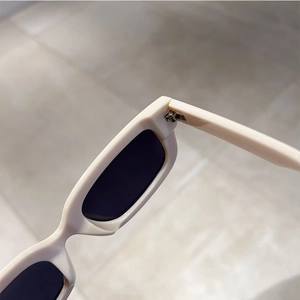 Detail of sturdy metal hinge on retro cream square sunglasses with dark lenses