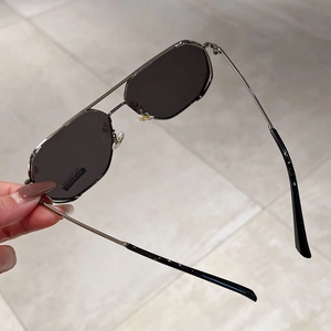 Close-up of silver metal pilot sunglasses with dark grey TAC polarized lenses being held