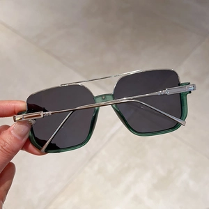 Close-up of green translucent semi-rimless sunglasses with dark gray polarized lenses