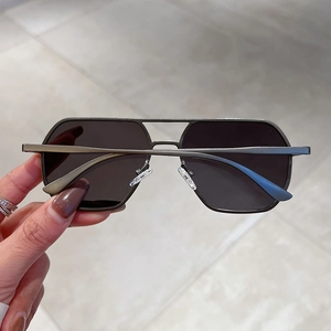 Close-up of gunmetal pilot sunglasses with double-bridge metal frame and dark grey lenses