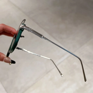 Detail view of dark green semi-rimless sunglasses with textured silver metal temples