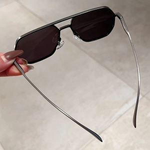 Detail of geometric black metal sunglasses featuring trendy double bridge and irregular lenses
