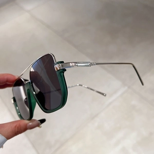 Close-up of semi-rimless sunglasses with dark green acetate and silver metal double bridge