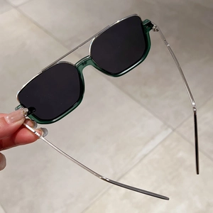 Detail view of semi-rimless sunglasses with dark green frames and silver metal temples