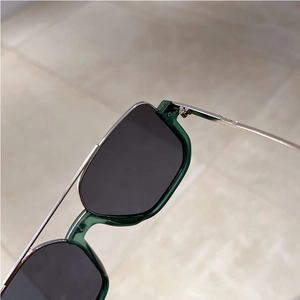Detail view of semi-rimless green sunglasses showing silver metal hinges and craftsmanship