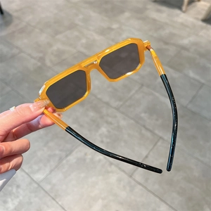 Detailed close-up of yellow transparent square frame sunglasses with black temple tips