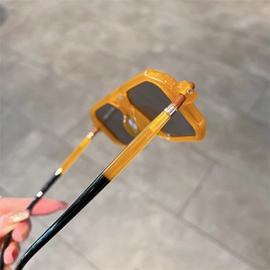 Detail shot of amber translucent frame and silver metal hinges on square sunglasses