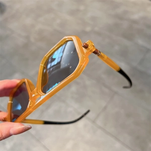 Close-up of translucent amber square sunglasses with thick frames and spherical hinges