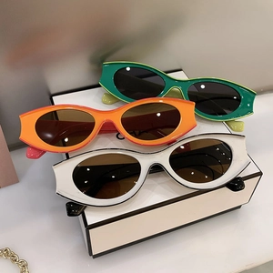 Close-up of retro oval cat-eye sunglasses in green, orange, and ivory colors
