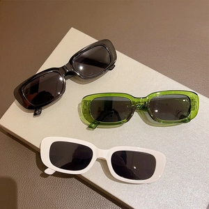 Close-up of rectangular retro sunglasses in black, transparent green and white frames
