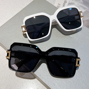 Detail of square oversized sunglasses showing thick frames and golden metal hinges