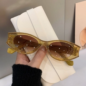 Detail of glitter cat eye sunglasses with brown gradient lenses and white textured case