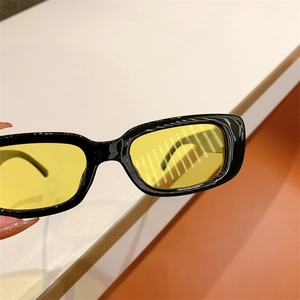 Detail of trendy rectangle sunglasses with black frame and translucent yellow lenses