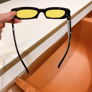 Detail view of vintage black square sunglasses with yellow lenses on a modern desk