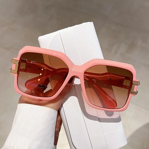 Pink square sunglasses with brown gradient lenses and gold hinge detail in a white case