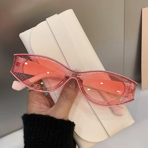 Detail of trendy pink glitter cat-eye sunglasses with translucent frame held by a model