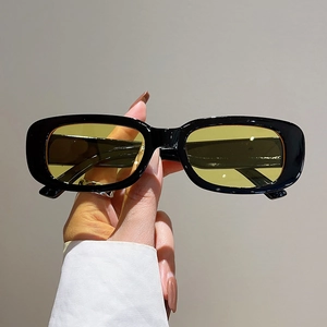 Detail view of vintage square sunglasses featuring black glossy frames and yellow lenses