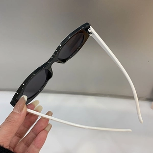 Detailed side view of cat-eye sunglasses with black oval frames and slim white temples