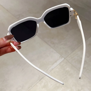 Detailed shot of white square frame sunglasses with gold temple metal hinge accents