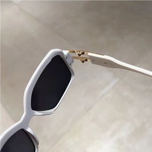 Detailed close-up of premium golden metal hinges on white square sunglasses frames