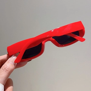 Detail view of glossy red rectangular sunglasses with dark lenses for retro street style