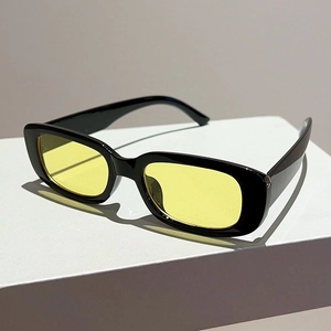 Retro rectangular sunglasses with black frames and yellow lenses on a white display stand
