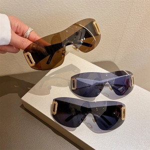 Close-up of Y2K shield sunglasses with metallic gold rectangle accents and textured crystals