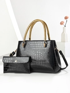 Detail of black crocodile texture handbag with golden braided handles and clutch bag