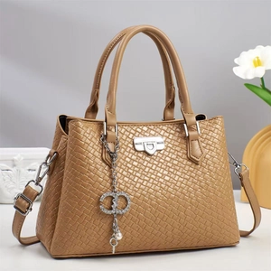 Close-up of woven texture and decorative metal keychain on tan crossbody handbag