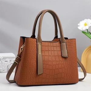 Détail du sac à main marron caramel avec texture crocodile et garnitures dorées