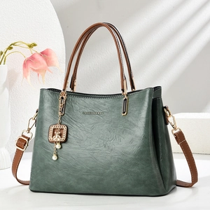 Green vintage leather tote bag with brown handles and a pearl pendant charm detail